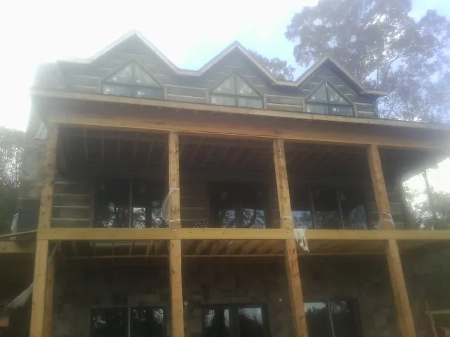 Dormers and porch framing on a large log home under construction — Roof Coating work by our crew in Palmer Lake