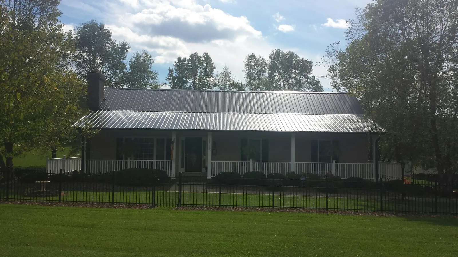 Gray metal roof on a brick ranch with a full width front porch — Gutter Guard Installation work by our crew in Palmer Lake