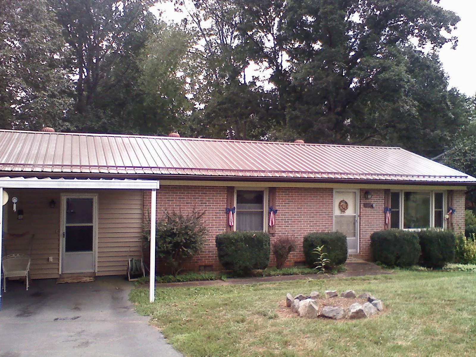 Bronze metal roof and carport on a brick ranch home — Roof Repair work by our crew in Palmer Lake