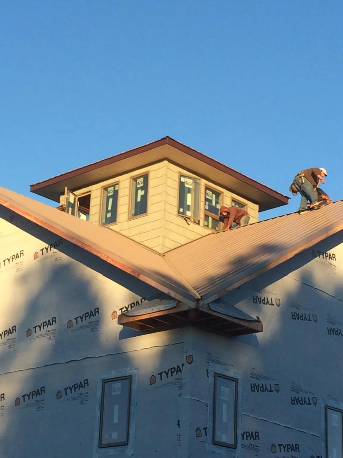 Roofers working around a rooftop cupola on a new metal roof at sunset — Roof Waterproofing in Palmer Lake by Roofing Brothers